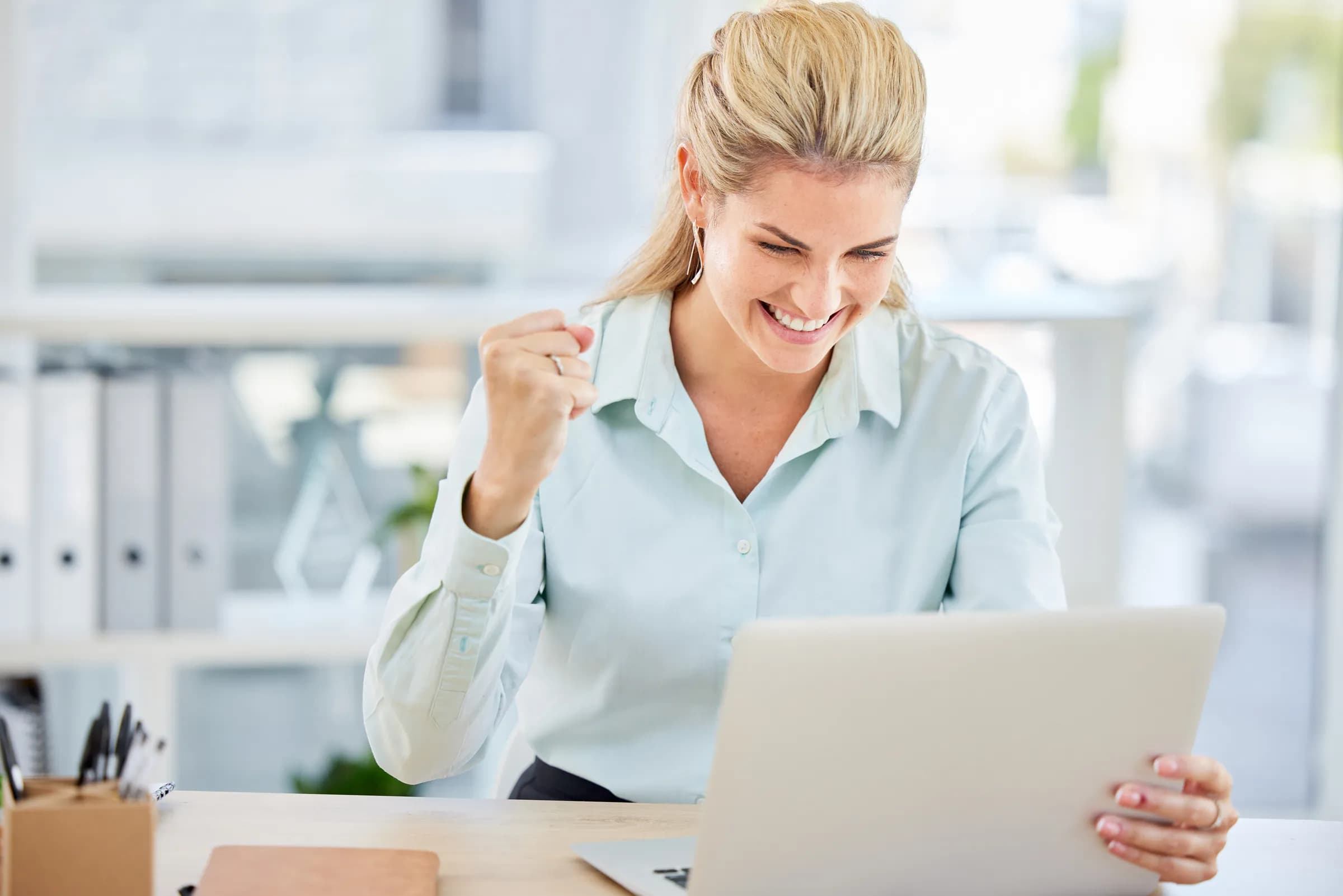 A business owner celebrating after winning a government contract at her laptop